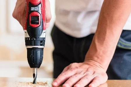 Person bohrt mit Akkuschrauber in Holz