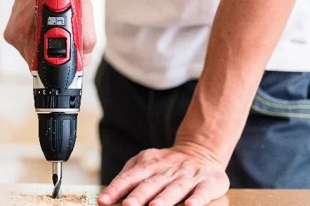 Person bohrt mit Akkuschrauber in Holz