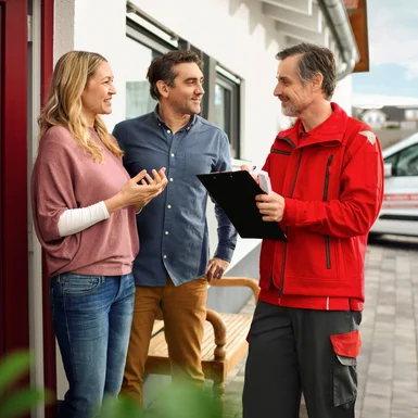 Drei Personen vor einem Haus