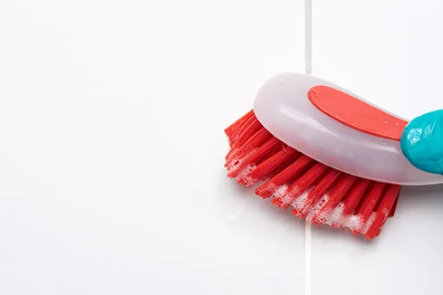 Hand in Handschuh schrubbt Fliesen