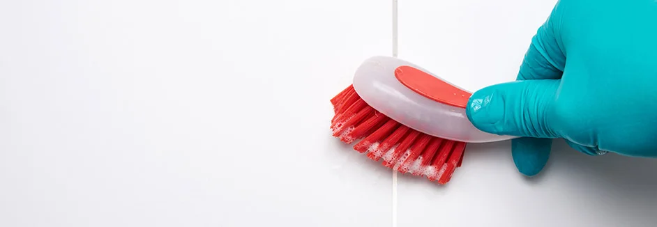 Hand in Handschuh schrubbt Fliesen