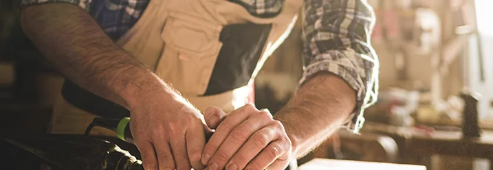 Person schleift Holz mit einem Schwingschleifer