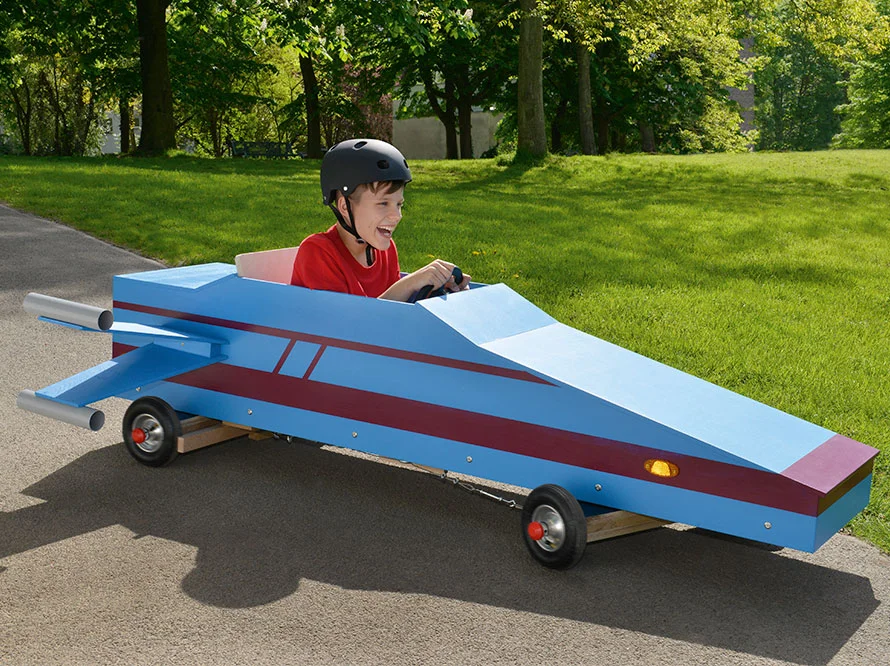 Lachendes Kind fährt blauen Seifenkiste