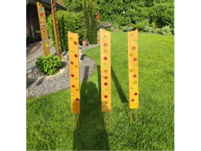 Drei hohe Holzdekorationen mit buntem Glaseinsatz im Garten