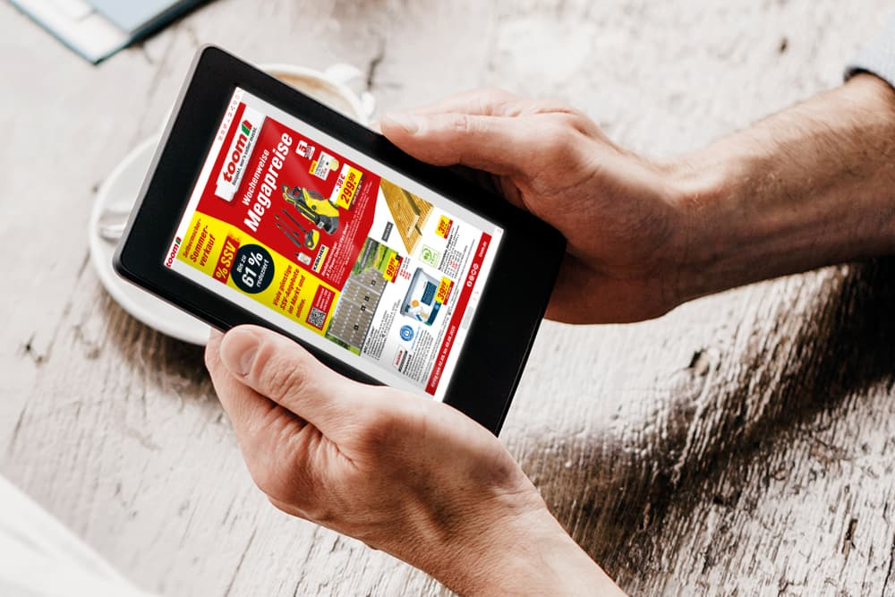 Eine Person hält ein Tablet, das die Angebote der Folgewoche anzeigt