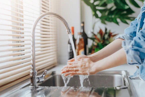 Person wäscht Hände unter Wasserhahn