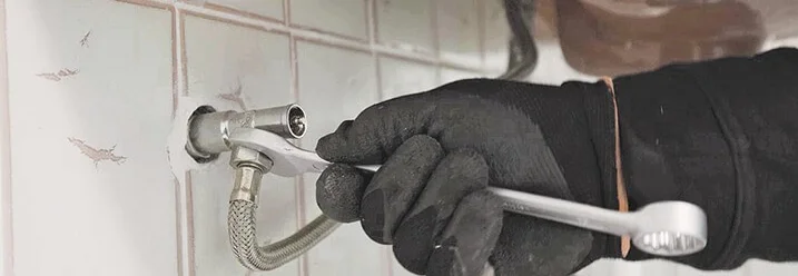 Hand mit Schraubenschlüssel an Rohr