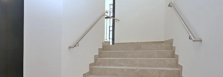Treppenhaus mit Steinstufen und Edelstahlgeländer