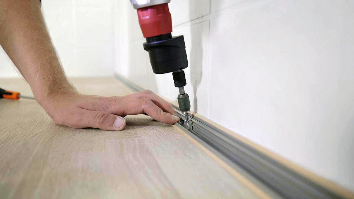Die Abschlusschiene wird zwischen Wand und Küchenplatte festgeschraubt.