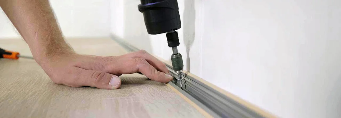 Person verschraubt eine Metallschiene auf dem Boden.
