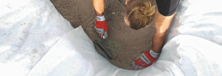 Person verteilt Sand mit Kelle