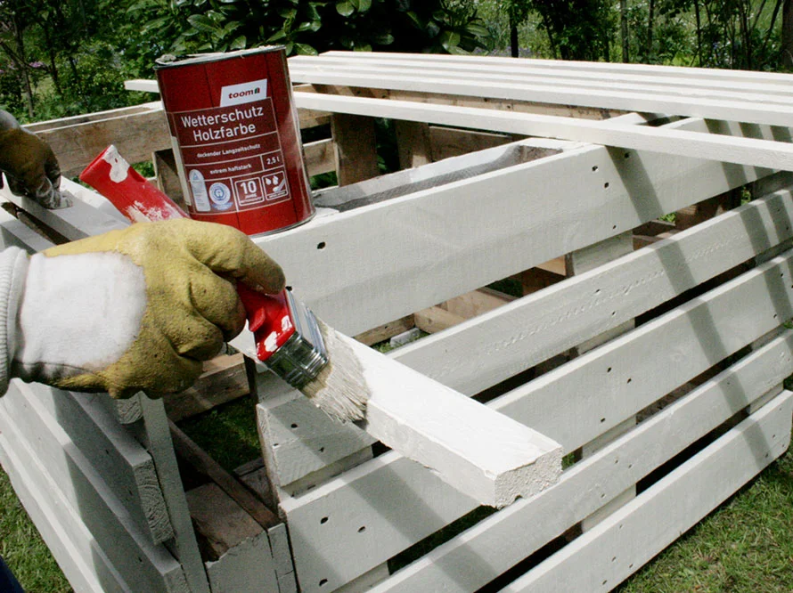 Person streicht Holz weiß an