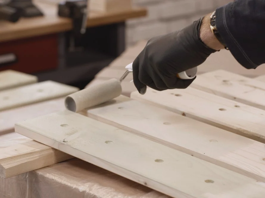 Person streicht Holzlatten weiß