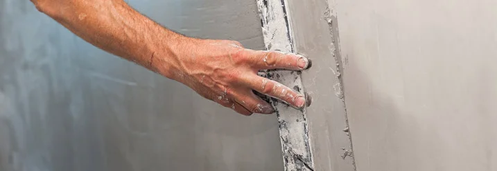 Person verputzt eine Wand mit Kelle.