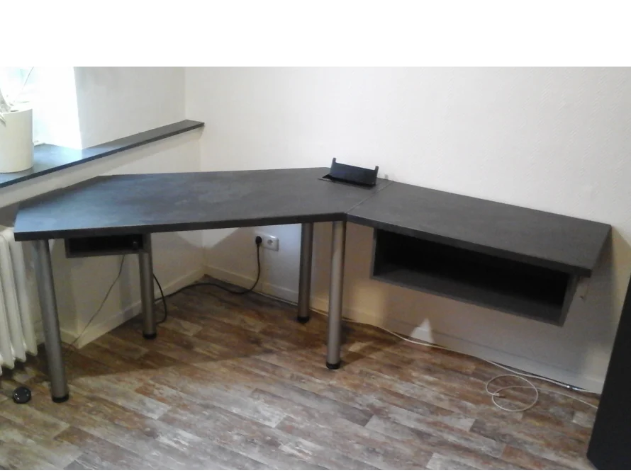 Ein grauer Eck-Computertisch mit silbernen Beinen.