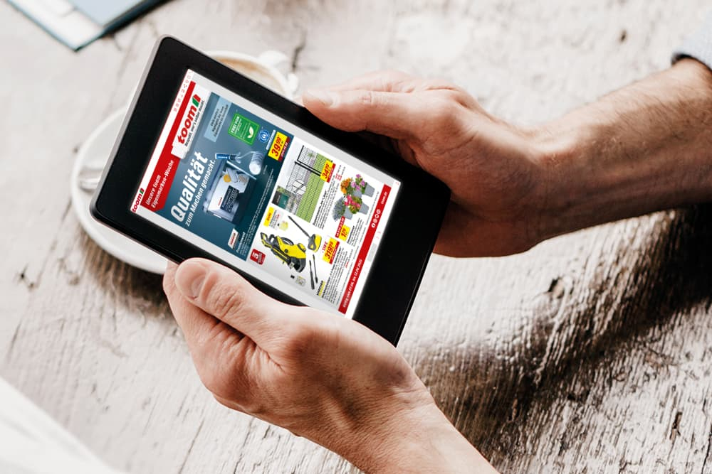 Hände halten einen Tablet mit einem Werbeprospekt