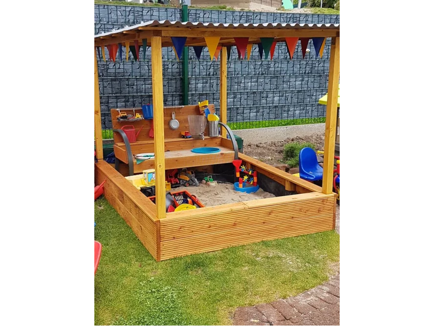 Überdachter Sandkasten mit Spielzeug