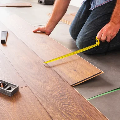 Person misst Laminat mit Zollstock