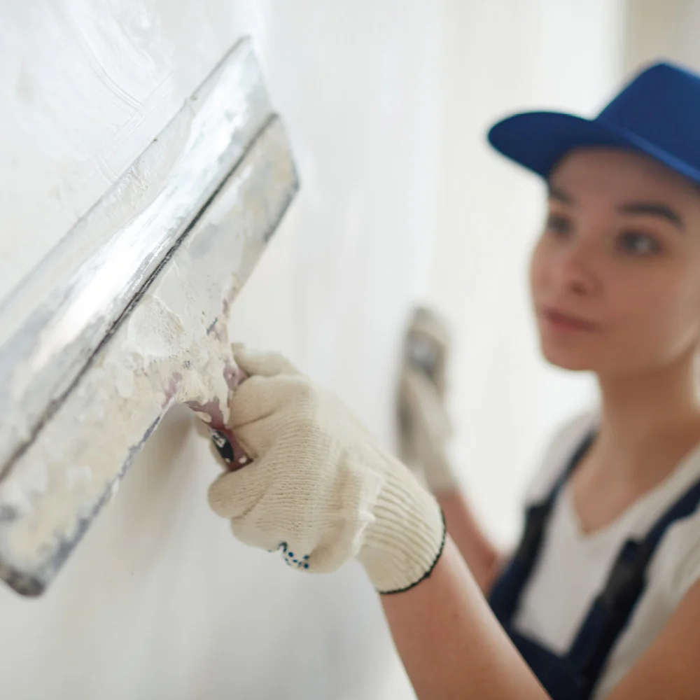 Person verputzt Wand mit Spachtel