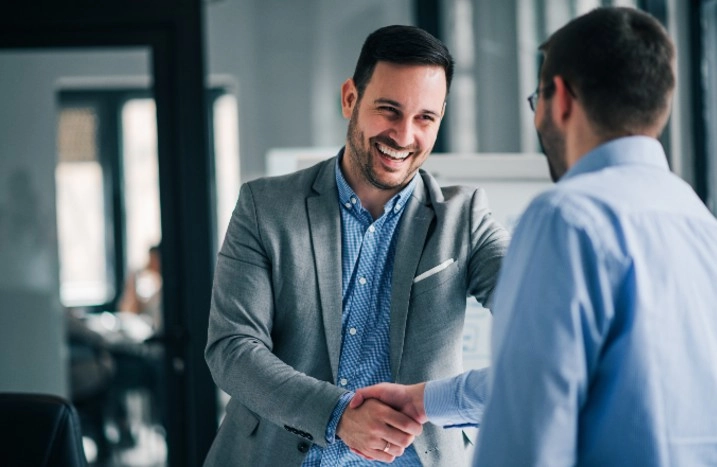 Zwei Personen im Anzug geben sich die Hand.
