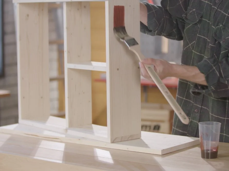 Person streicht ein Holzregal mit einem Pinsel