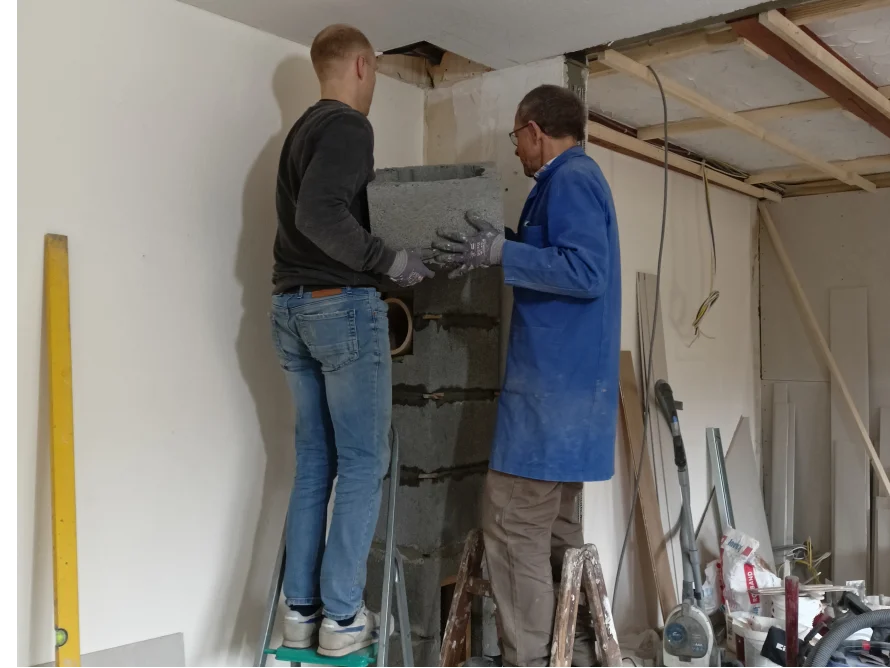 Zwei Personen mauern einen Schornstein