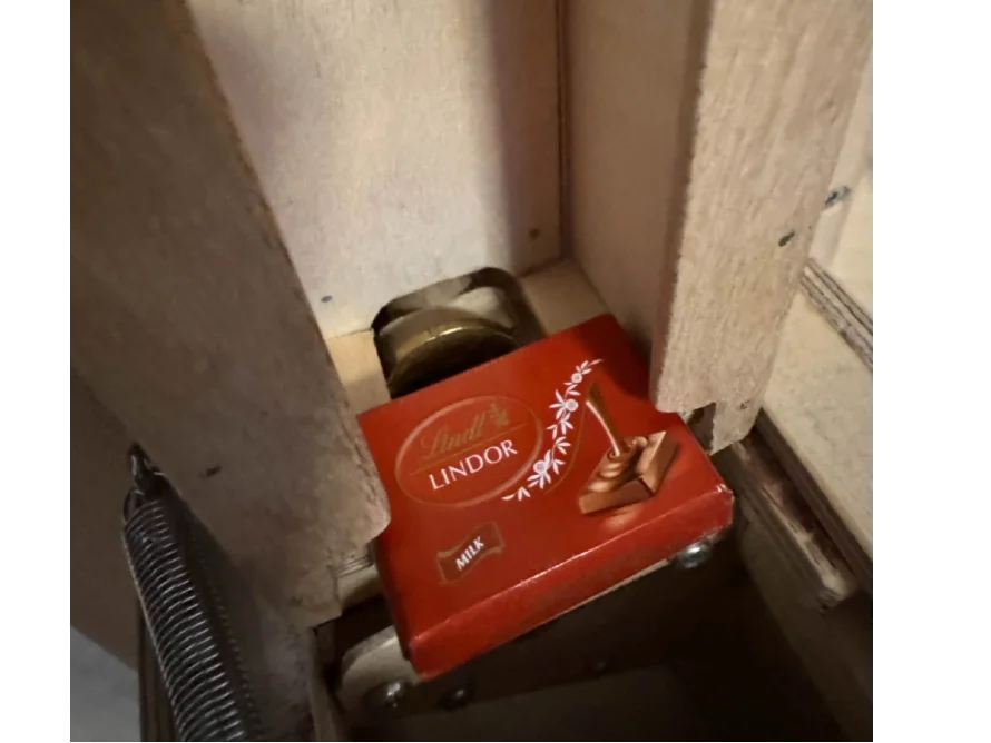 Eine Packung Pralinen klemmt in einem Holzrahmen.