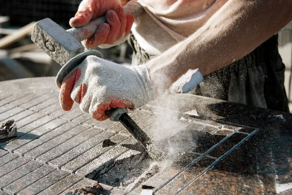 Person meißelt Stein