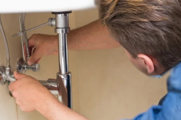Person repariert einen Wasserhahn.