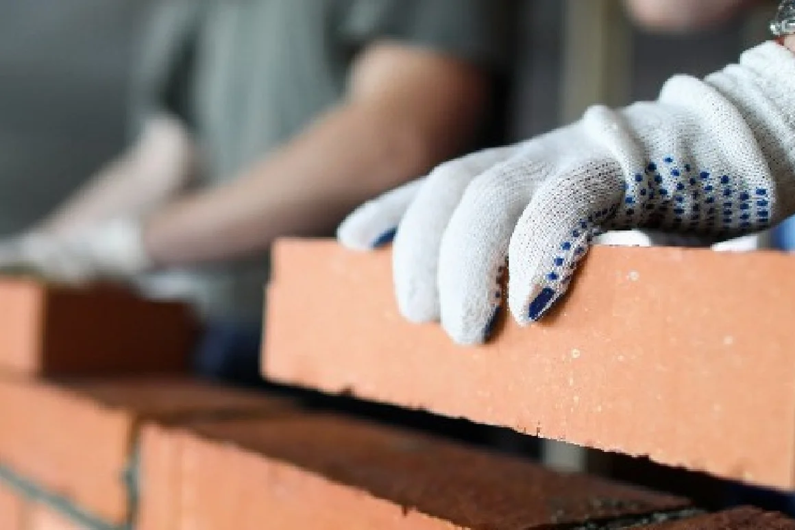 Person mauert Ziegelsteine