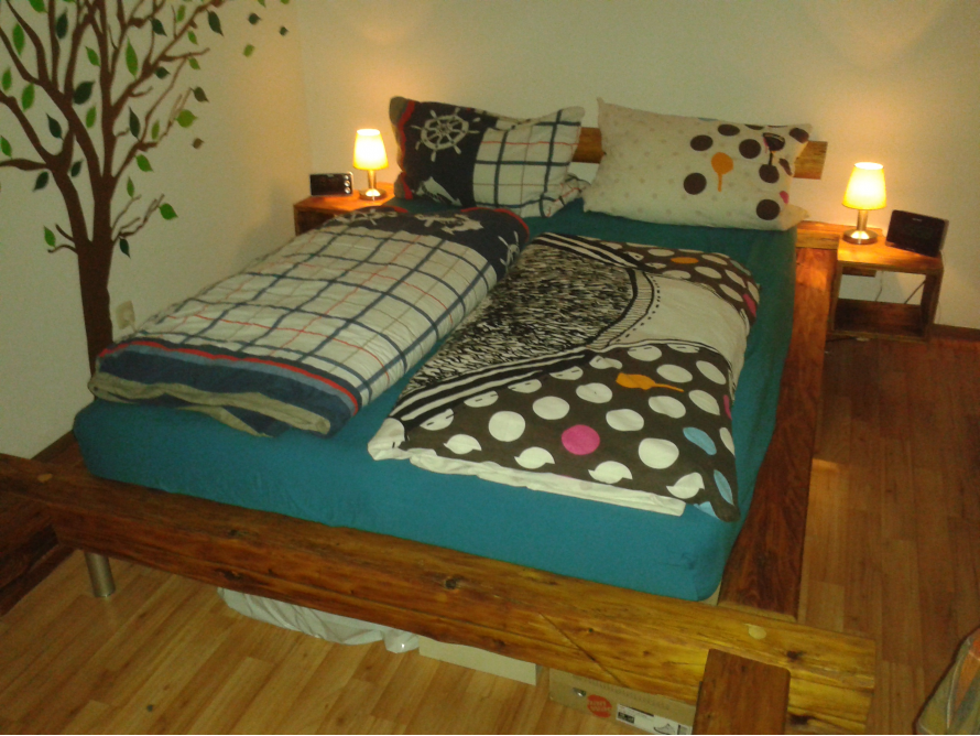 Holzbalkenbett mit Nachtkästchen