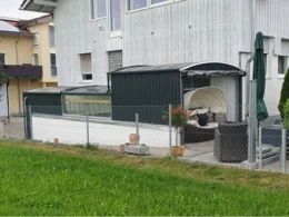 Eine dunkelgrüne Poolüberdachung mit Lounge-Möbeln auf einer Terrasse.