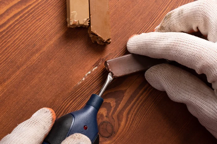 Person repariert Holzplatte mit Werkzeug