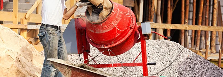 Person füllt Zement in Betonmischer