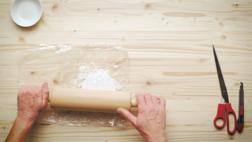 Hände rollen Teig mit einem Nudelholz aus