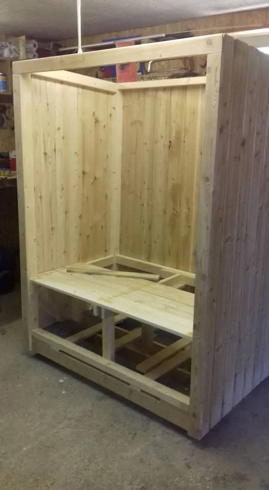 Eine unfertige Holzkabine mit einer Sitzbank im Bau.