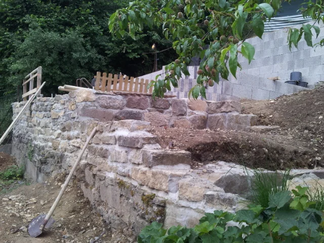 Unfertige Natursteinmauer mit Spaten