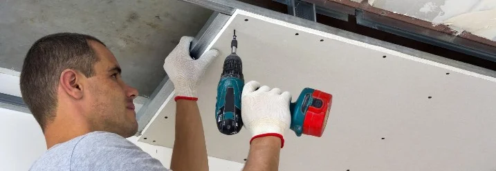 Person befestigt Trockenbauwand mit Akkuschrauber an Decke
