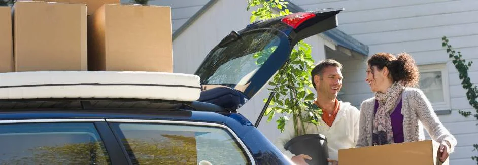 Ein Paar lädt einen Kombi mit Umzugskartons beladen.