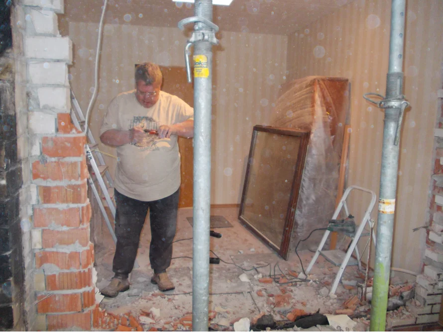 Person entfernt Wand mit Meißel