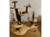 Ein mehrstöckiges Baumhaus-Spielzeug aus Holz mit Leitern, Schaukeln und kleinen Figuren.