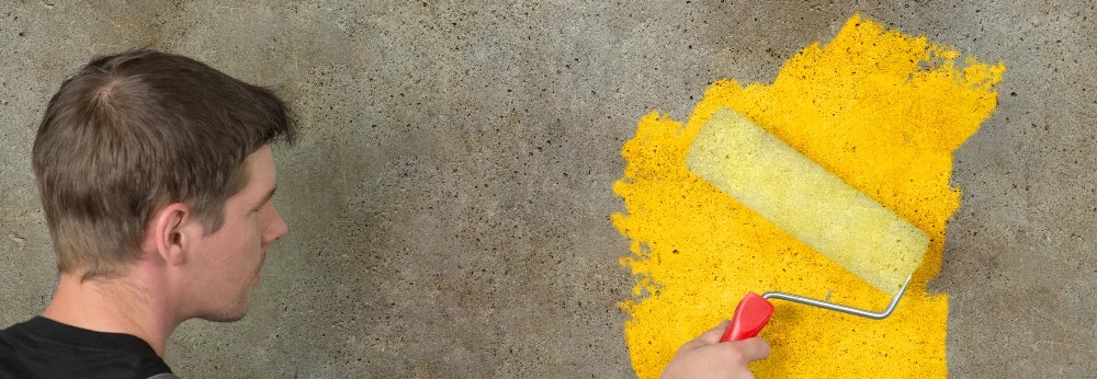 Person streicht Wand gelb