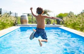 Ein Junge springt in einen Pool.