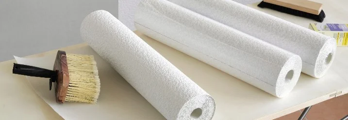 Drei Rollen weiße Raufaser auf Tapeziertisch