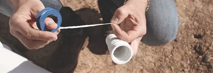 Person wickelt Teflonband um ein Rohr.