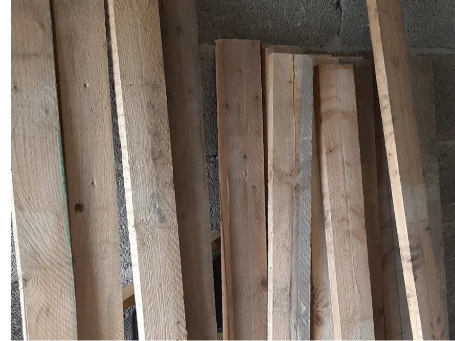 Ein Stapel Holzbretter an einer Betonwand.