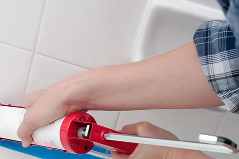 Person trägt Dichtmittel mit Kartuschenpistole auf