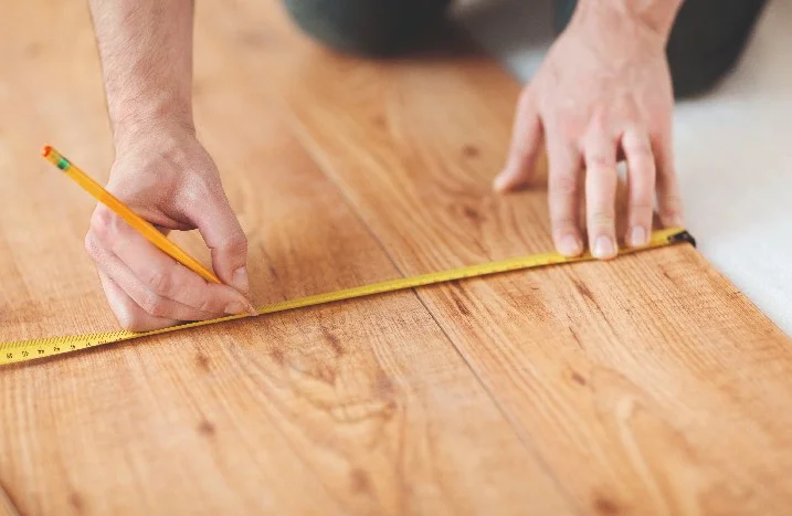 Person vermisst Holzboden mit Zollstock.