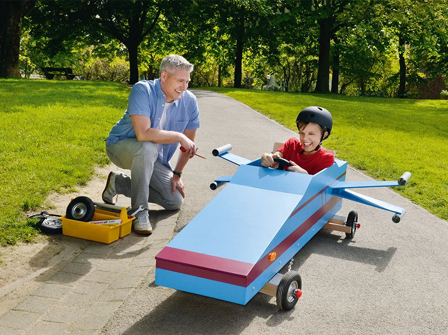 Person repariert Seifenkiste mit Schraubendreher