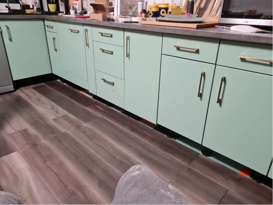 Mintgrüne Küchenschränke auf grauem Laminat